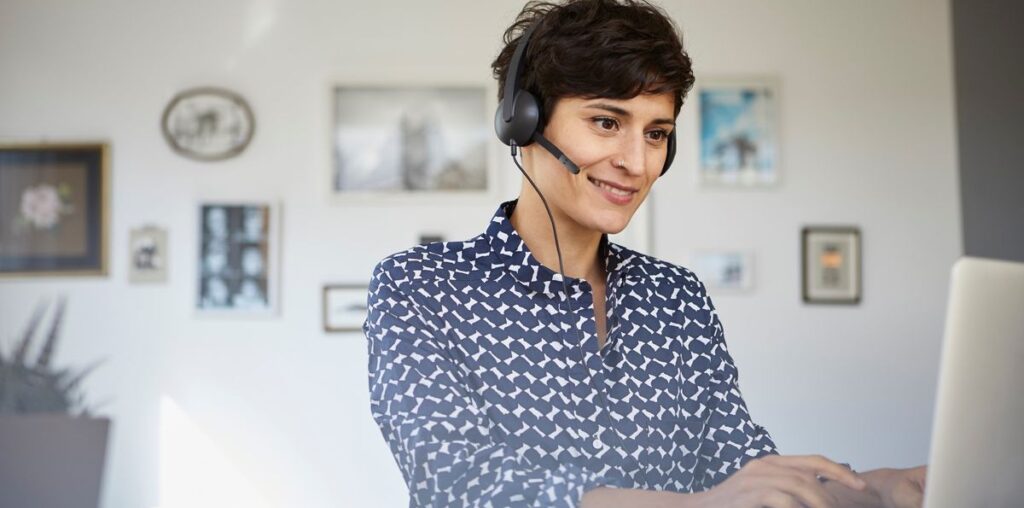 Person using a laptop while earing a headset with microphone.