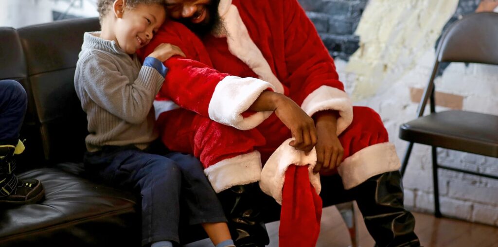 Isaac Holbert (left) enjoyed the company of Santa Claus, portrayed by Eddie A. Brimage at the Black Market in Boston on Dec. 7.