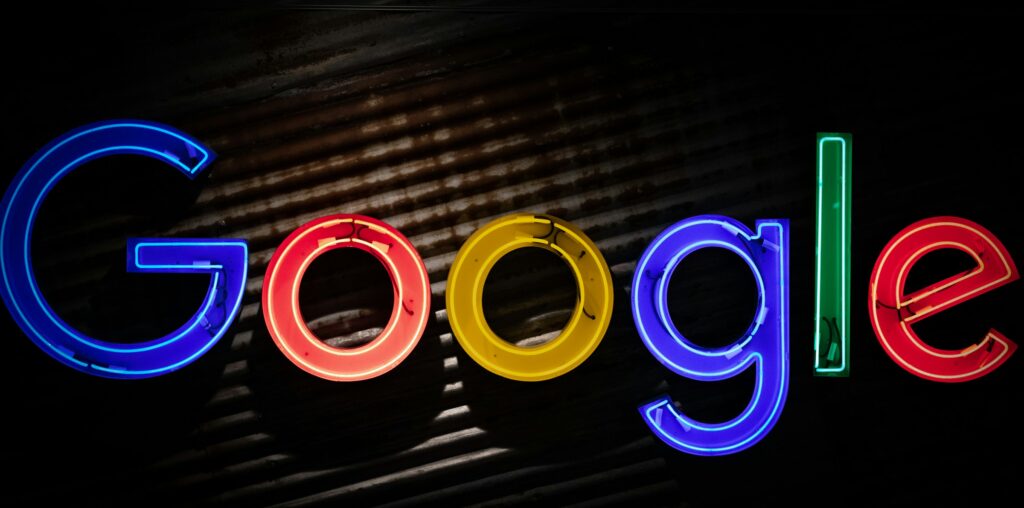 Google logo neon sign as the company announces a restructuring of its divisions and leadership to accelerate its AI initiatives.