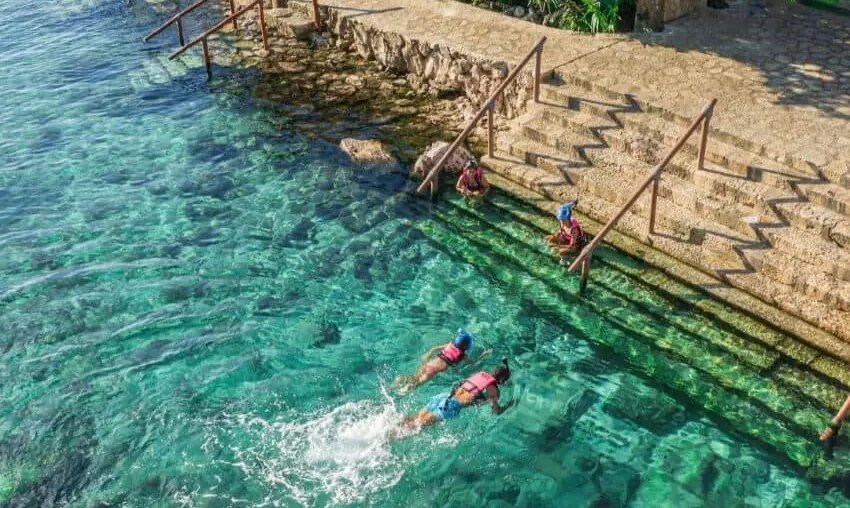 Two people swim in the turquoise waters of the Xcaret Hotel in Quintana Roo