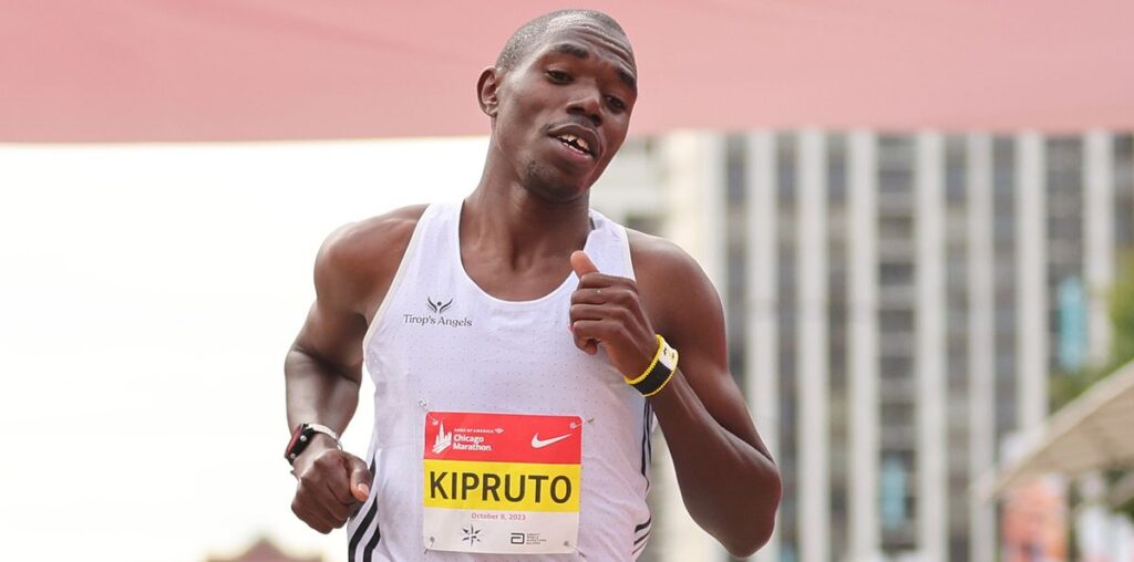 Kipruto of Kenya, wearing a white running vest, crosses the finish line ahead of the 2024 Chicago Marathon