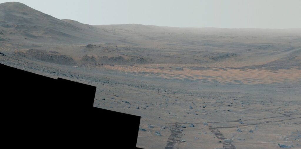 looking down the slope of a crater rim on mars, with rover tracks in the foreground