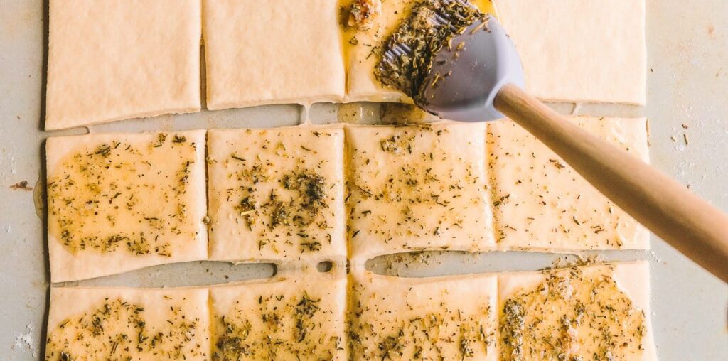 Brushing pull apart garlic bread with herb butter.