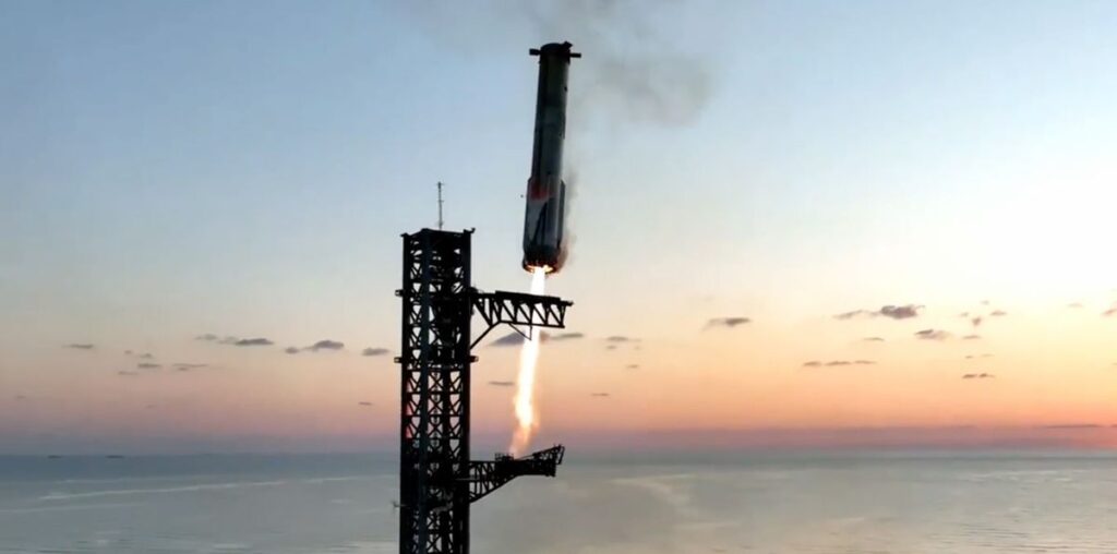 a huge rocket comes in for a landing beside its seaside launch tower