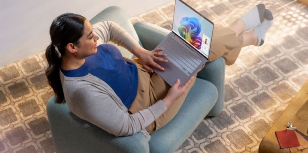 A woman sitting in a chair looking at a Windows 11 laptop