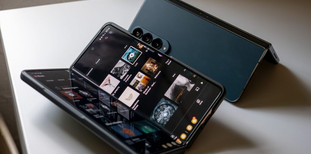 A Samsung Galaxy Z Fold 5 running YouTube Music next to a Greygreen Galaxy Z Fold 4