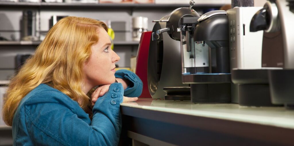 Woman looking at coffee makers on shelf in store