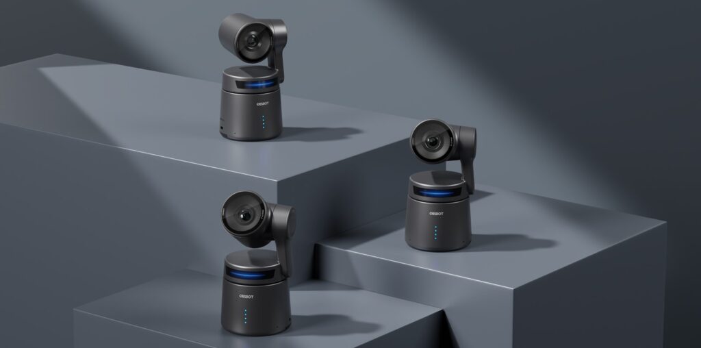 Three black security cameras are displayed on geometric gray platforms. Each camera has a sleek, modern design with blue accent lights. The background is minimal and monochromatic, focusing on the cameras.