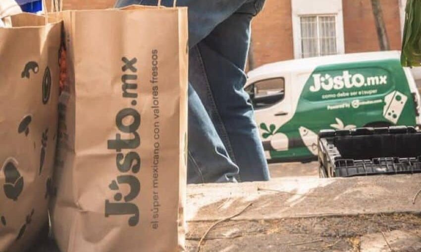 A delivery person from Mexican company Jüsto holds a pair of paper bags