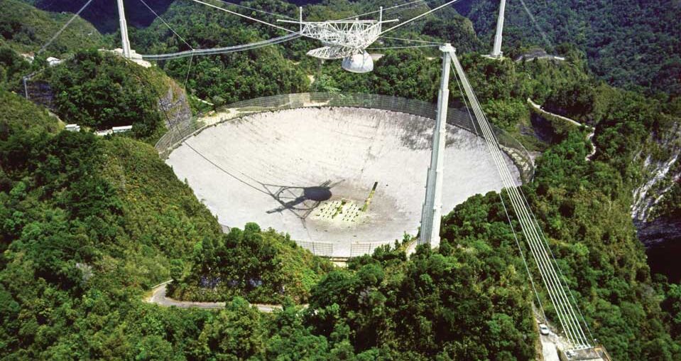 an aerial shot of a large cement disc in the midst of trees