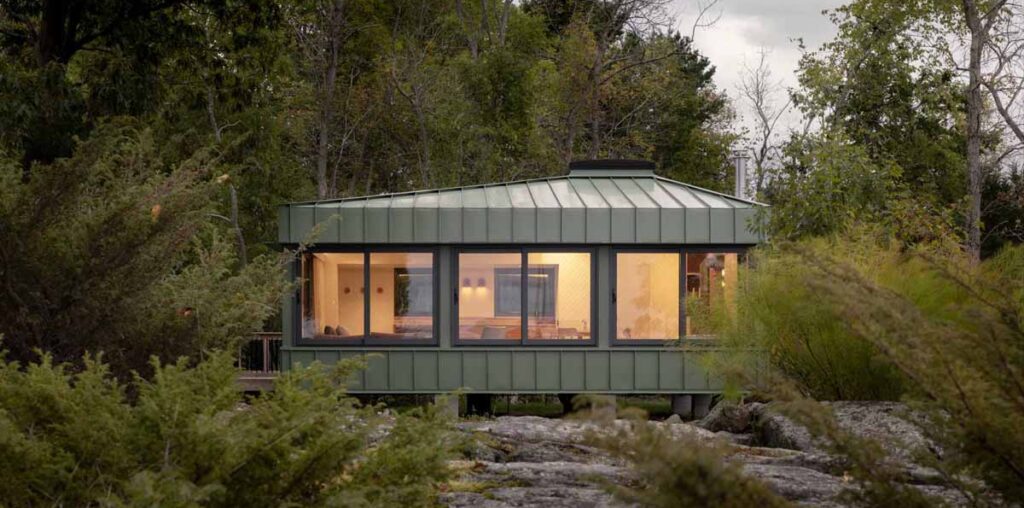 Green Metal Siding Allows This Small Cottage To Blend In With Its Surroundings