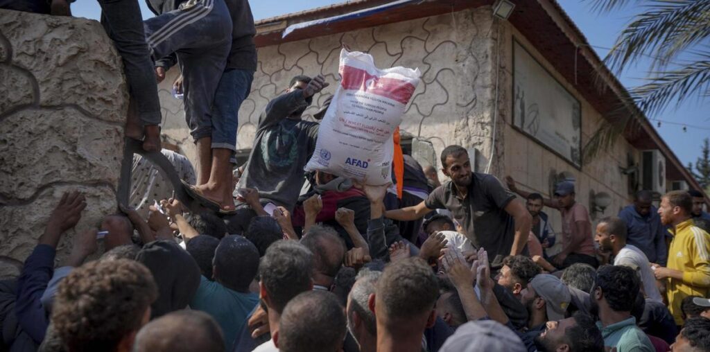 Habitantes del centro de Gaza reciben sacos de harina de la UNRWA en Deri al Balah.