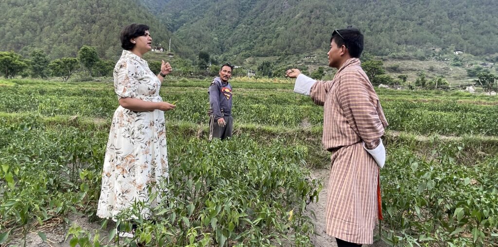 Two people stand in a chili field in Punakha, Bhutan.