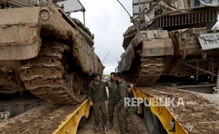 Israeli soldiers stand next to Merkava tanks from the Reserve Brigade 4 loaded on trucks after they pulled out from southern Gaza Strip, at an undisclosed location in Israel, 28 January 2024. More than 26,200 Palestinians and at least 1,330 Israelis have been killed, according to the Palestinian Health Ministry and the Israel Defense Forces (IDF), since Hamas militants launched an attack against Israel from the Gaza Strip on 07 October 2023, and the Israeli operations in Gaza and the West Bank which followed it.