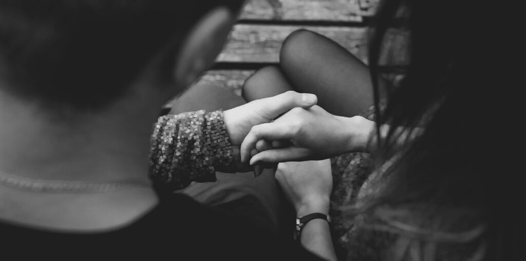 A closeup of two people's hands, clasping each other, as seen between their two heads.