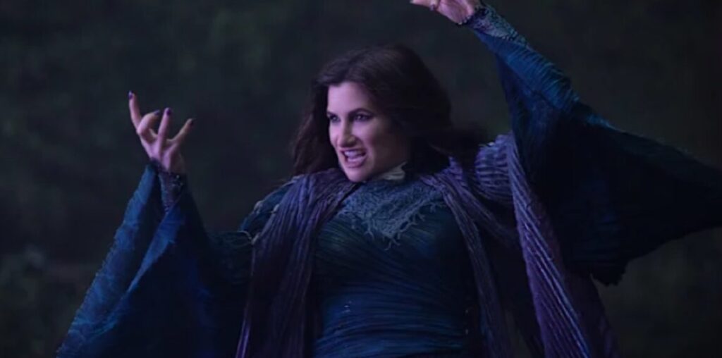 Dark-haired woman in witch's robes with arms aloft, about to cast a spell