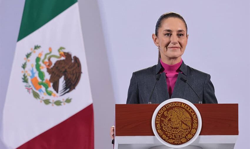 Mexican President Claudia Sheinbaum stands at a podium during her morning press conference in front of a Mexican flag