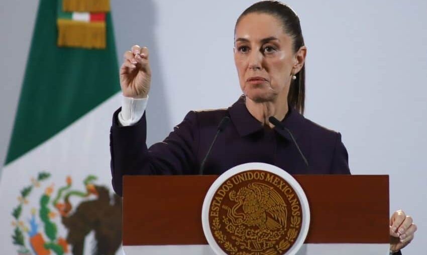 President Claudia Sheinbaum holds up her closed right hand while making a point while standing at the presidential podium during her Nov. 21 press conference at Mexico's National Palace.