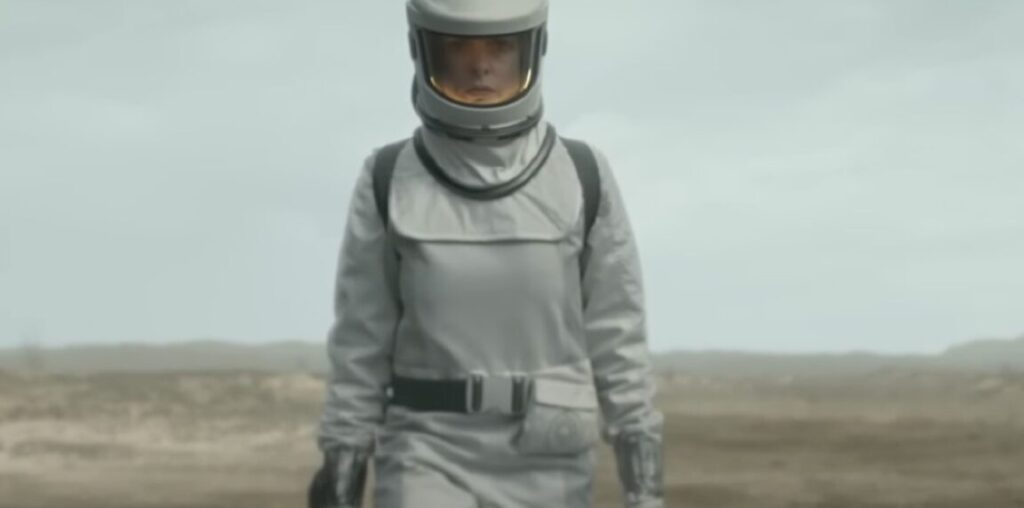 woman in white space suit walking across a desolate plain