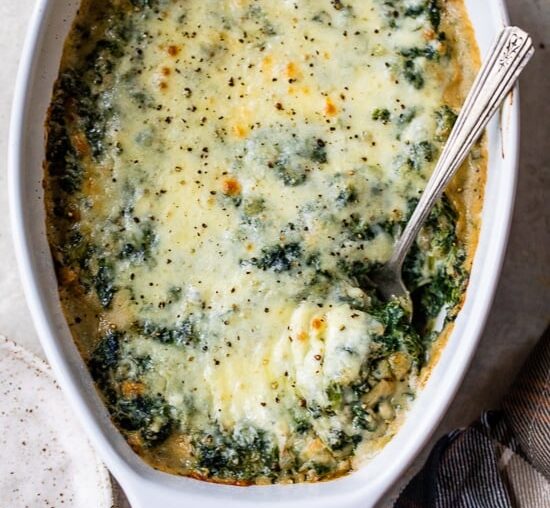 Spinach Gratin in a casserole dish with a serving spoon.