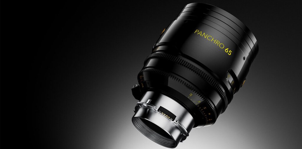 A close-up of a Panchro 65 camera lens against a dark, gradient background. The lens features prominent focusing and zoom rings, with yellow text indicating its model. The lens is angled, highlighting its intricate design and metal housing.