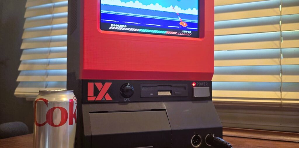 A replica LX System game console inspired by the UFO 50 video game sitting on a wooden desk next to a can of diet Coke.