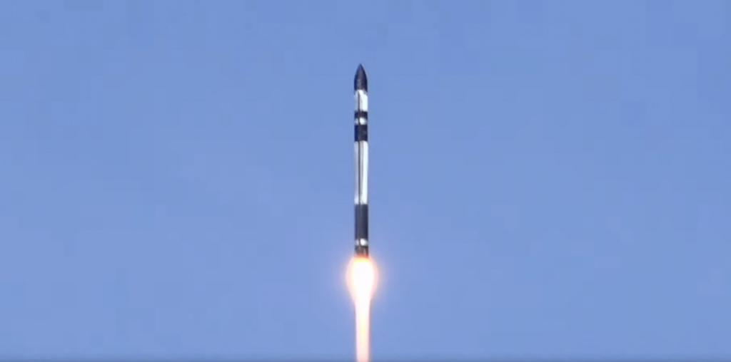 a black and white rocket launches into a blue sky